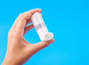 Person holding a white asthma inhaler