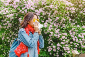Woman blowing her nose by plants