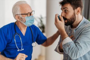Doctor showing a man how to use an inhaler