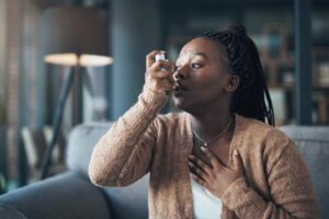Cropped shot of an attractive young woman using a pump during an asthma attack in her living room