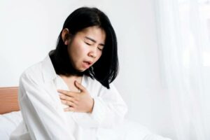 Asian woman having panic disorder in bed hand holding her chest