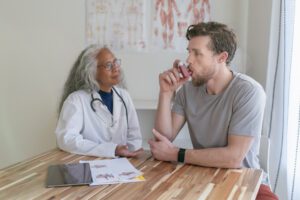 Young adult male in medical consultation learning how to use an inhaler