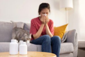 Woman Sneezing While Cuddle Her Cat on Sofa Suffer From Cat Fur Allergy Symptom